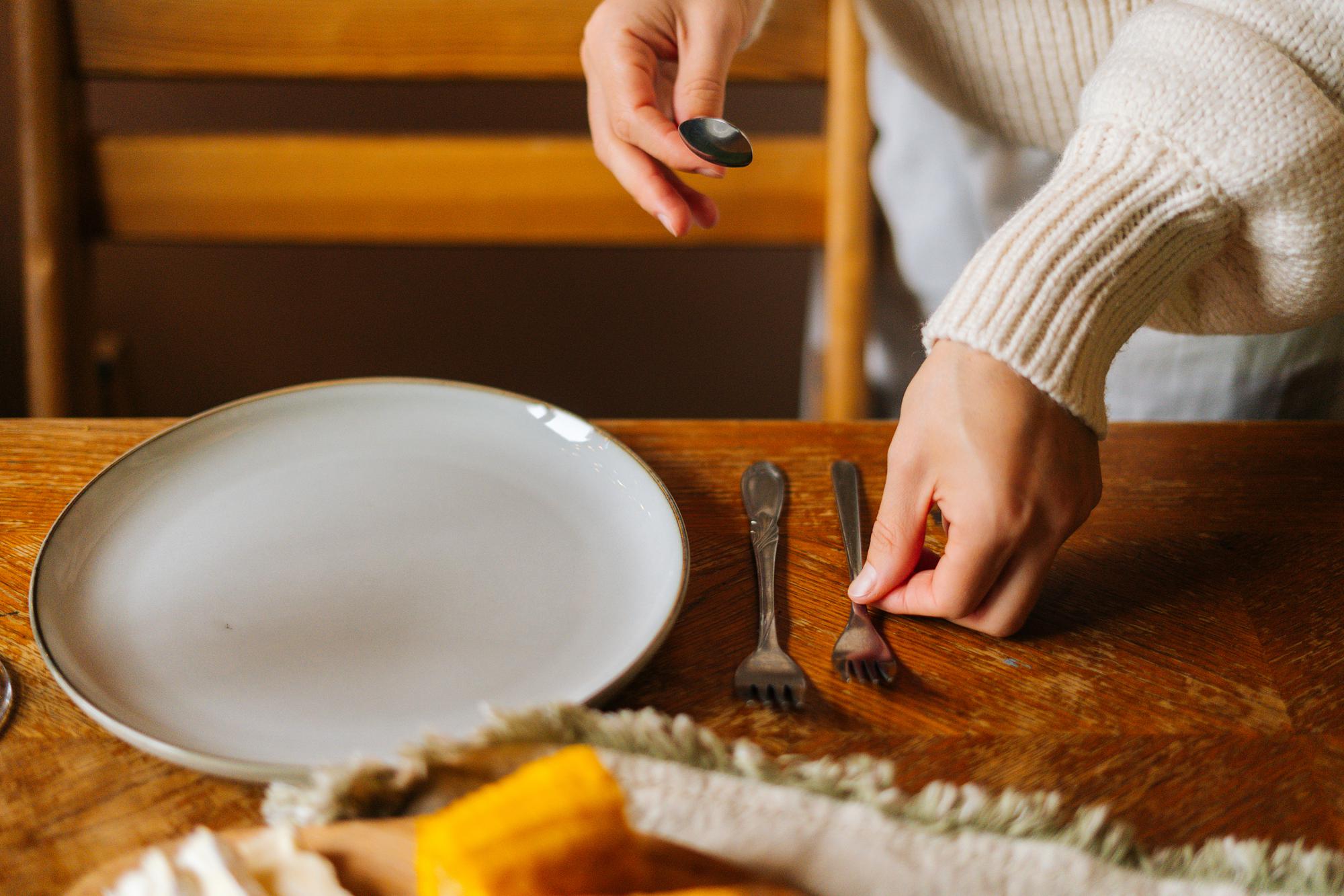 close-up of hands plating a composed dish on a wooden table